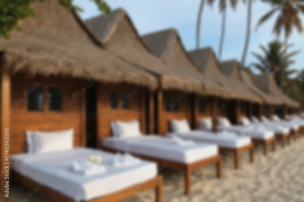 Obraz premium blurry background of white sand beach with wooden houses and sun beds for visitors.