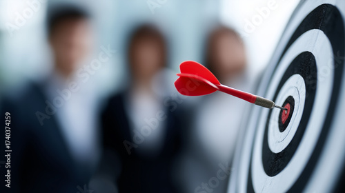 Closeup of dart in center of target, blurred business people in background symbolizing teamwork success dart in bullseye, teamwork success, blurred businesspeople, strategy focus,