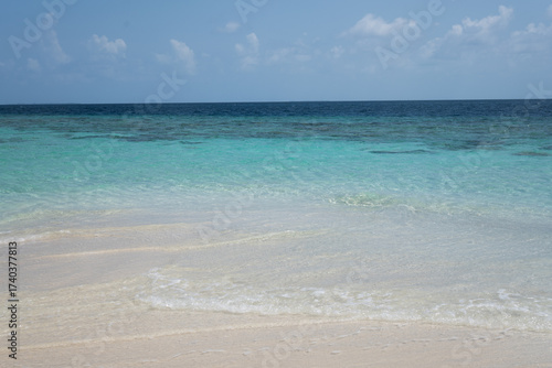 Turquoise tropical sea with gentle waves on sandy beach