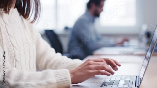 Focused work: A person diligently works on a laptop in a modern office, highlighting concentration and productivity in a professional setting.