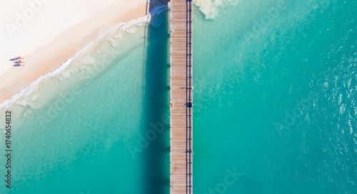 Drone aerial of pier extending into turquoise sea