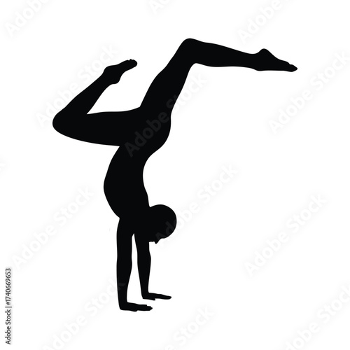 Silhouette of a flexible gymnast performing an impressive handstand with legs extended in the air