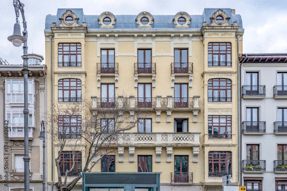 Naklejka premium Historic Building on Plaza del Castillo, Pamplona, Spain. Belle Epoque Architecture, Yellow Facade, Mansard Roof, City Center Square, Urban Heritage