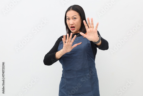 Картината върху платно Young Asian woman wearing apron on white background with disgust, displeasure and fear expression showing dislike, rejection, reluctance reaction