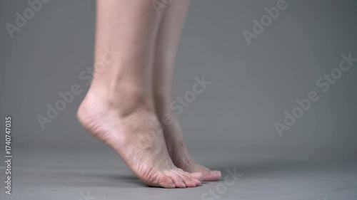 Individual leg training on a gray studio background, bare feet, demonstrating foot position and stability
