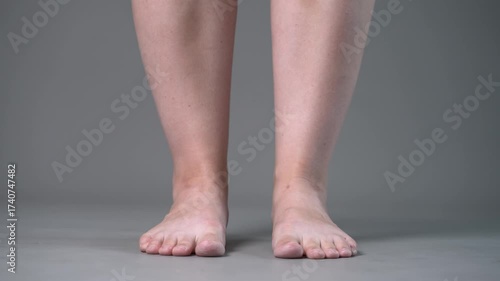 Individual leg training on a gray studio background, bare feet, demonstrating foot position and stability