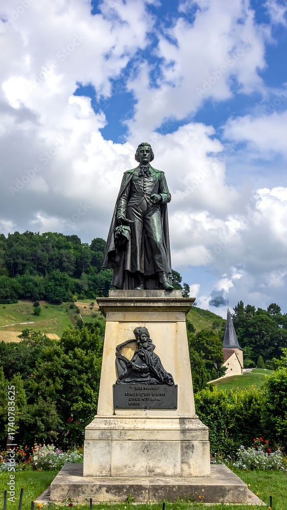 Fototapeta premium Bronze statue atop plinth against lush greenery and cloudy sky