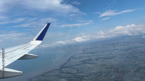 Aerial footage from airplane window showing wing and coastal landscape
