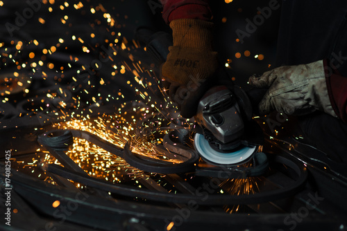 Intense sparks fly off the angle grinder as a worker shapes a custom wrought iron piece in a dramatic close-up view.