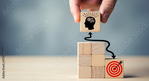 Hand Places Head with Gears Cube Atop Wooden Blocks With Arrow and Target Cube