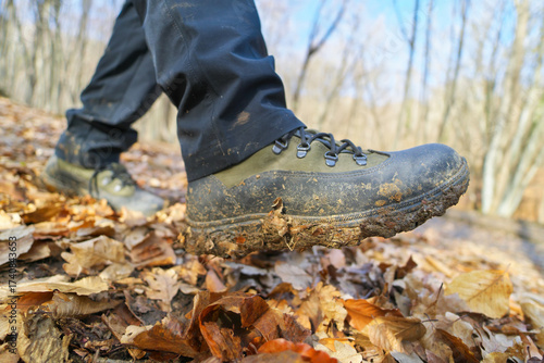 Close-up of muddy hiking boots walking on a wet, dirt path.