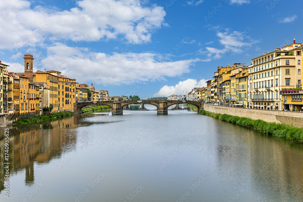 Fototapeta premium View of the of Arno River with Santa Trinita Bridge and Florence's stunning architecture the banks and a clear blue sky above