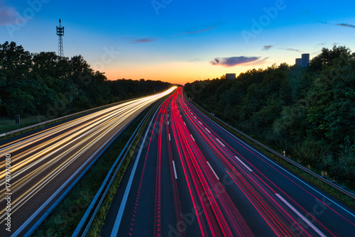 Langzeitbelichtung einer deutschen Autobahn bei Sonnenuntergang – Lichtspuren von Fahrzeugen, dynamischer Verkehr und stimmungsvolle Dämmerungsatmosphäre