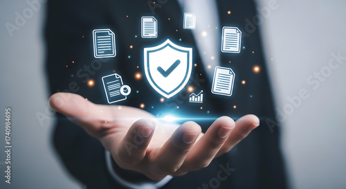 A hand holding a shield icon with document icons floating above, representing data protection and cybersecurity in business