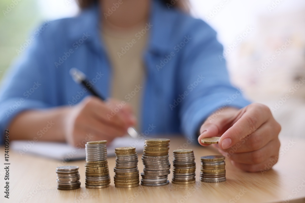 Fototapeta premium Woman counting coins at wooden table indoors, selective focus