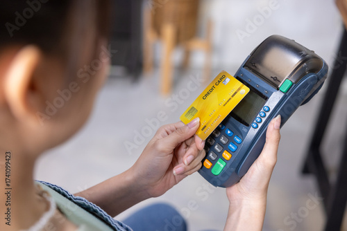 Smiling woman holding credit card and payment terminal
