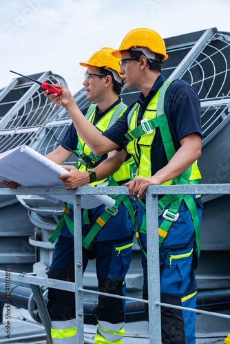Engineers reviewing blueprints on rooftop HVAC site