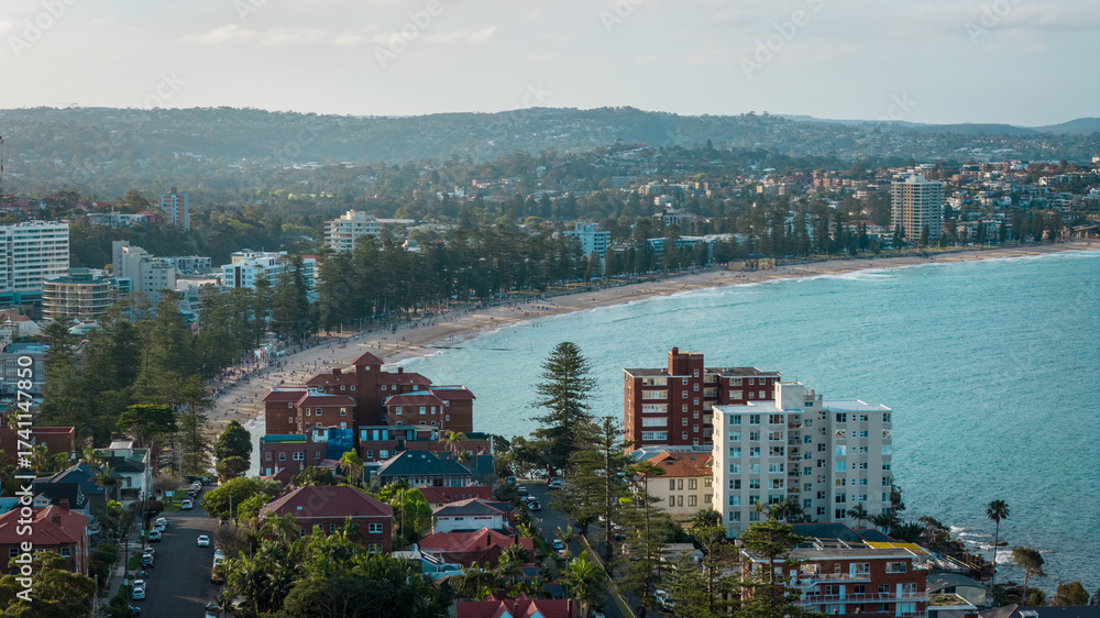 Obraz premium Stunning panoramic views of Manly Beach with soft golden sands and gentle waves glistening beneath the clear blue sky.
