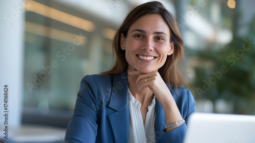 Portrait of confident businesswoman smiling warmly at camera while working efficiently on laptop in well lit corporate office space | professional portrait business confidence Free Download Portrait of confident businesswoman smiling warmly at camera while working efficiently on laptop in well lit corporate office space | professional portrait business confidence - GFXLoad