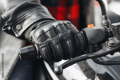 man hand in black leather glove on motorcycle handle, close up view, safety on road, riding motorcycle concept