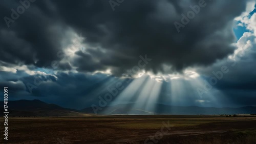 Dramatic landscape features dark, ominous clouds, with light shafts illuminating a field and distant mountains. The ground is brown