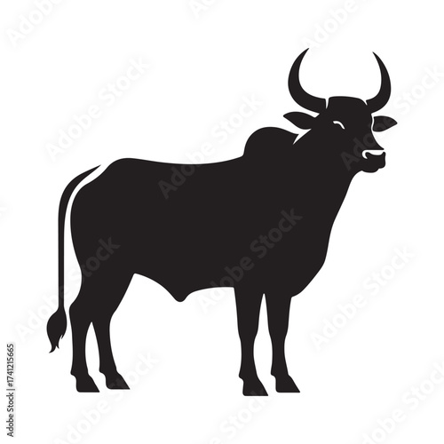 Silhouette of a majestic bull with prominent horns standing on a grassy field