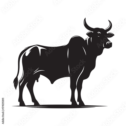 Silhouette of a majestic bull with prominent horns standing on a grassy field