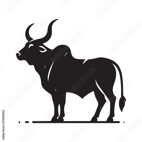 Silhouette of a majestic bull with prominent horns standing on a grassy field