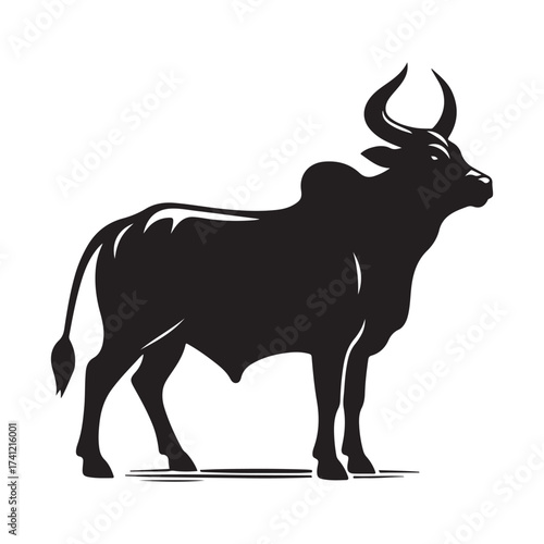 Silhouette of a majestic bull with prominent horns standing on a grassy field