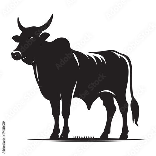 Silhouette of a majestic bull with prominent horns standing on a grassy field