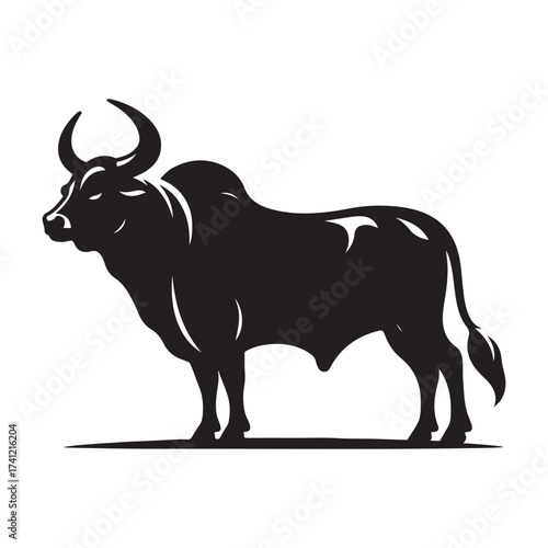 Silhouette of a majestic bull with prominent horns standing on a grassy field