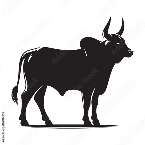 Silhouette of a majestic bull with prominent horns standing on a grassy field