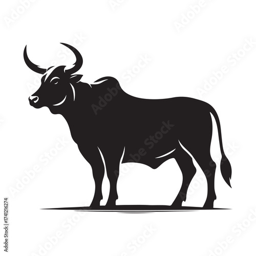 Silhouette of a majestic bull with prominent horns standing on a grassy field