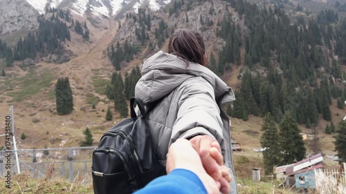 Couple holding hands while walking towards mountain scenery
