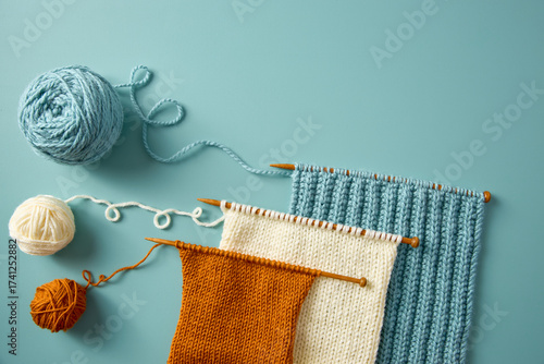Obraz na plátně Flat lay of colorful knitting samples in blue, white, and orange yarn on wooden needles