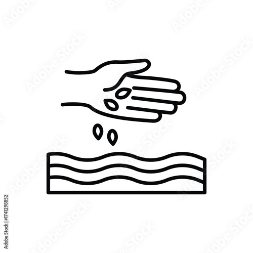 A hand drops seeds onto wavy soil