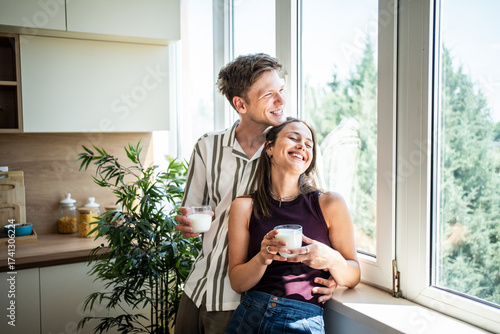 Happy couple enjoying morning milk in kitchen