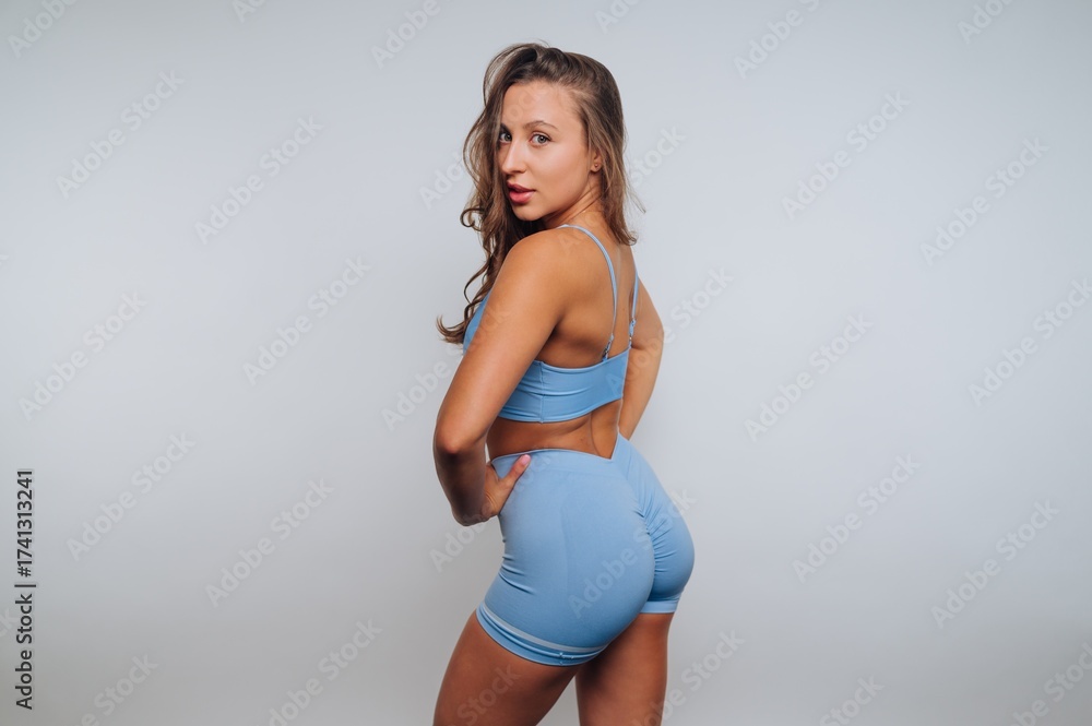 Obraz premium Woman posing in fitted blue clothing with a playful expression in a studio setting