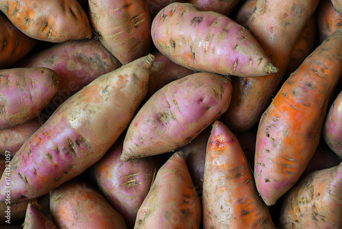 A solid background filled with wet earthy sweet potatoes with tapered ends