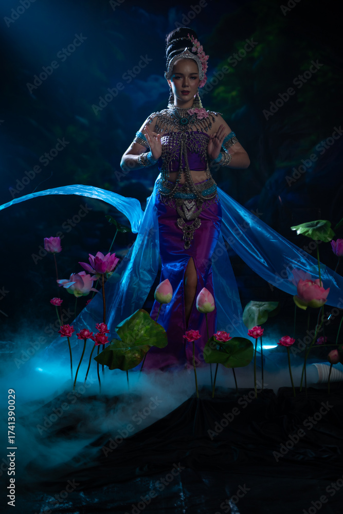Fototapeta premium Elegant woman in traditional Southeast Asian costume dancing gracefully among lotus flowers