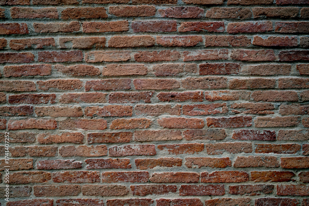 Fototapeta premium A brick wall with a rough texture and a reddish-brown color