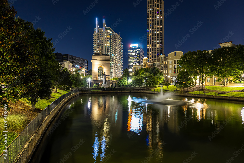 Fototapeta premium Illuminated arch monument in Atlanta at night with city buildings in background