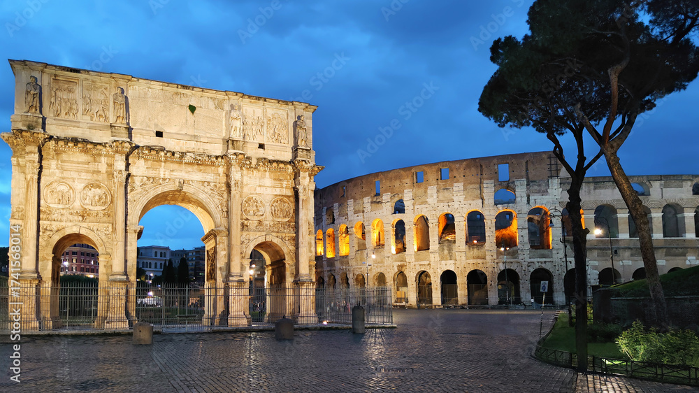 Fototapeta premium The iconic Colosseum and the Arch of Constantine beautifully illuminated against the dramatic blue hour sky in Rome, Italy. An ancient and majestic historical landmark, a popular tourist destination