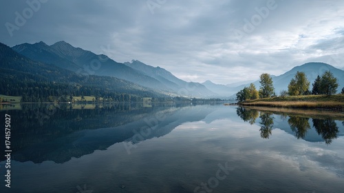 Serene lake landscape with mountains in the background mirror-like water soft light and clouds peaceful early morning mood