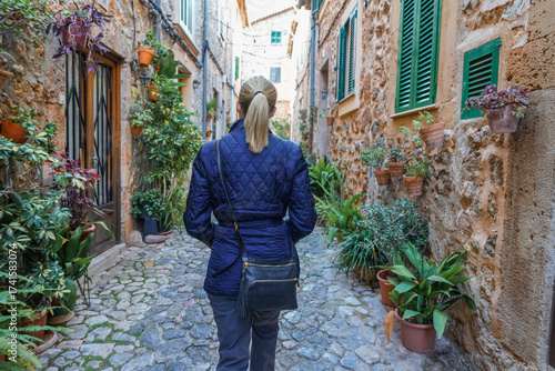 Woman walking through plant filled alley in Valldemossa Spain