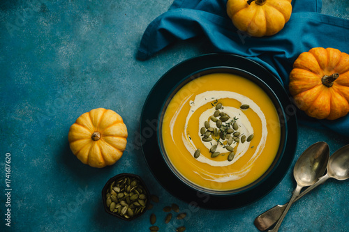 Pumpkin soup in a blue bowl, blue background. Autumn food