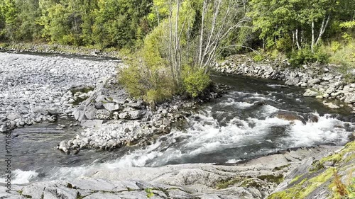 The river flows over rocks and runs near the autum