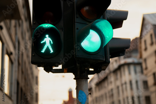 Fotografie Traffic lights showing green pedestrian walk signal and green car light at city