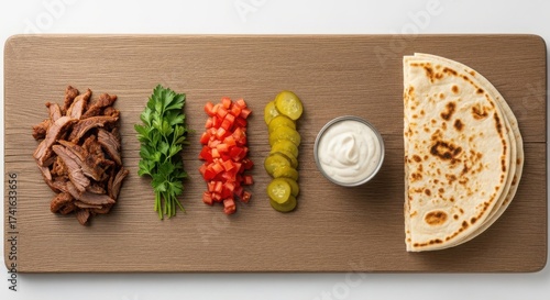 Deconstructed shawarma ingredients arranged neatly on a wooden board sliced meat, fresh parsley, chopped tomatoes, pickles, garlic sauce, and a folded flatbread