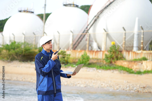 Environmental engineer or ecological scientist industrial worker in safety uniform working for inspect water quality at industry construction site near oil refinery plant by the sea.